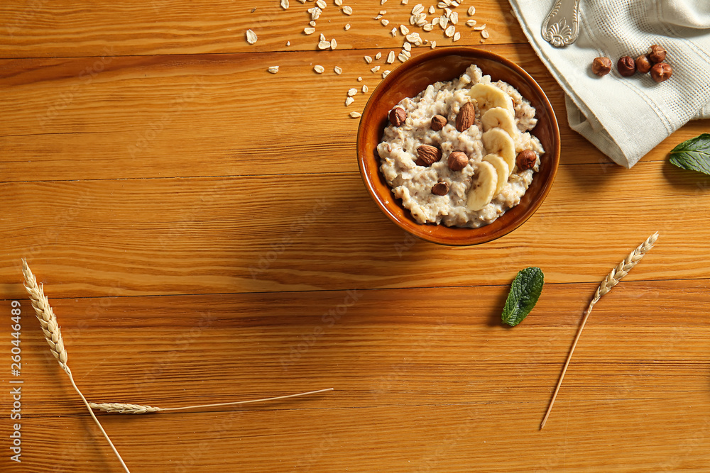 Bowl with tasty sweet oatmeal on wooden table