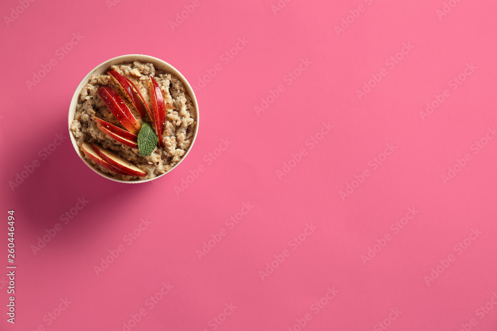 Bowl with tasty sweet oatmeal on color background