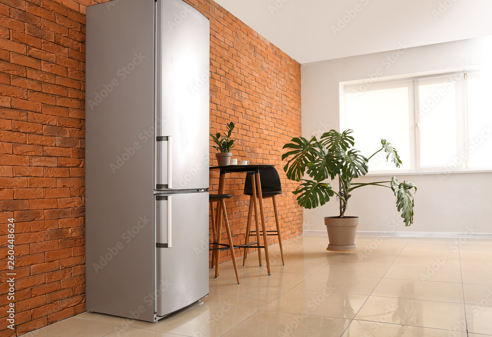 Modern fridge, table and chairs in kitchen