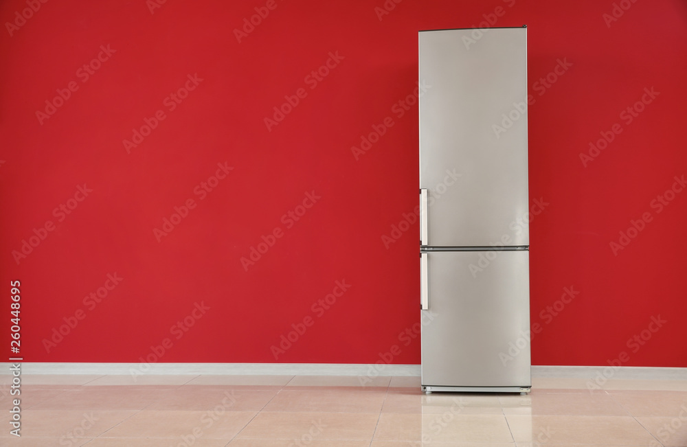 Modern fridge near color wall