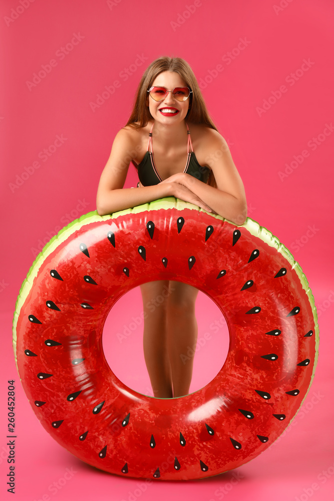 Beautiful young woman with inflatable ring on color background