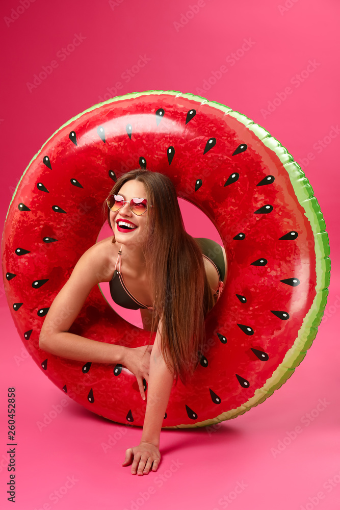 Beautiful young woman with inflatable ring on color background