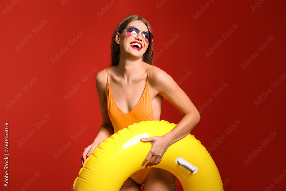 Beautiful young woman with inflatable ring on color background