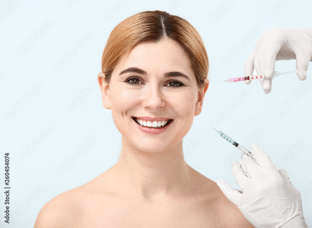 Beautiful woman and hands holding syringes for anti-aging injections on white background