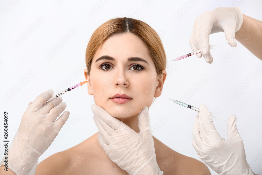 Beautiful woman and hands holding syringes for anti-aging injections on white background