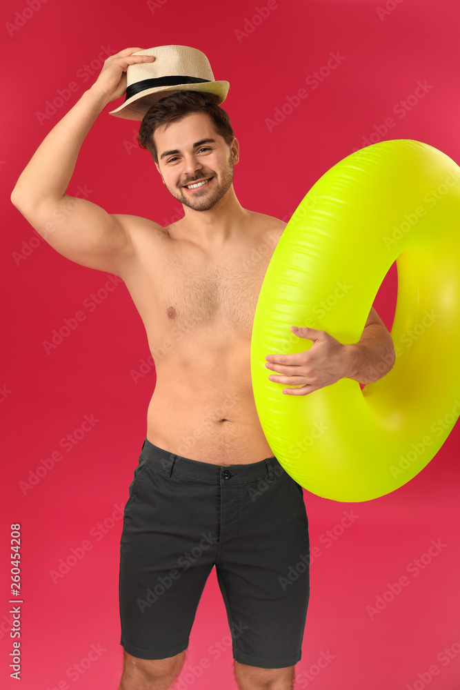 Handsome man with inflatable ring on color background