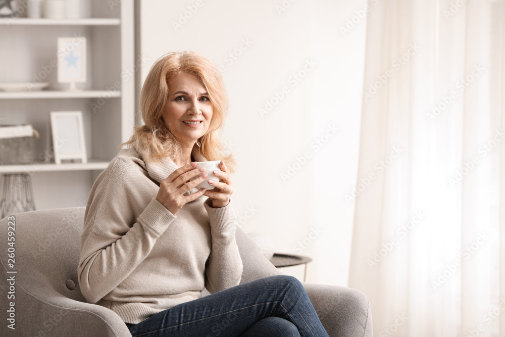 Stylish mature woman drinking coffee at home