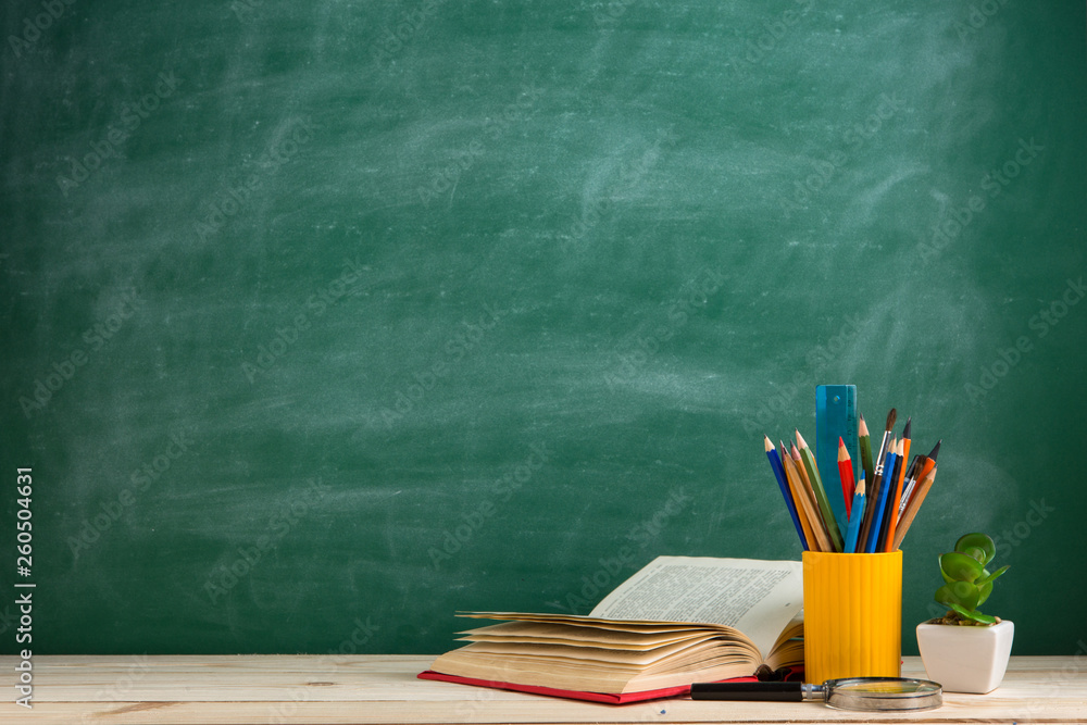 Education and reading concept - group of colorful books on the wooden table in the classroom, blackb