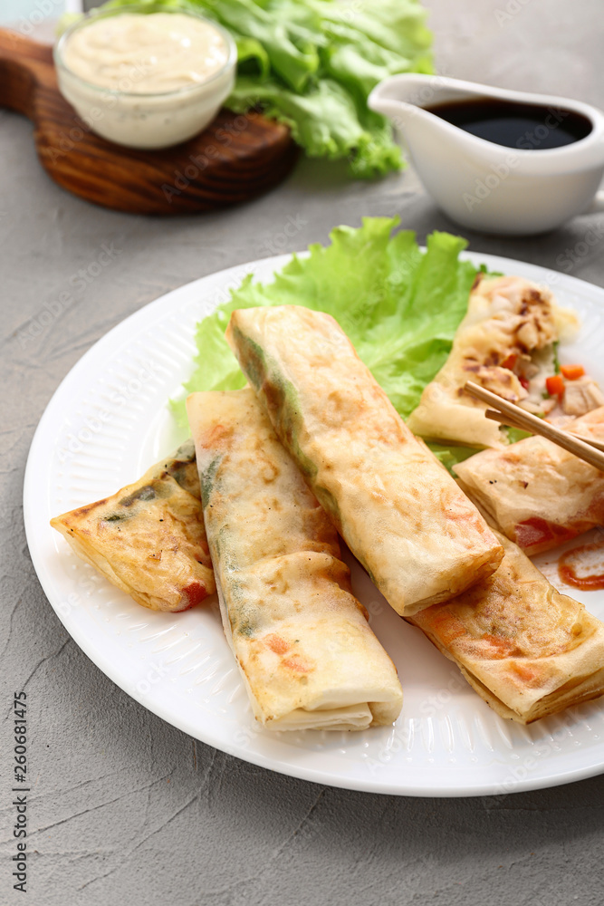 Plate with tasty fried spring rolls on table