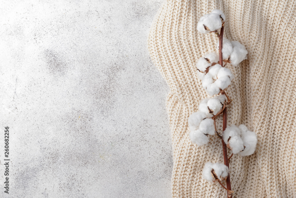 Cotton flowers with knitted plaid on grey background