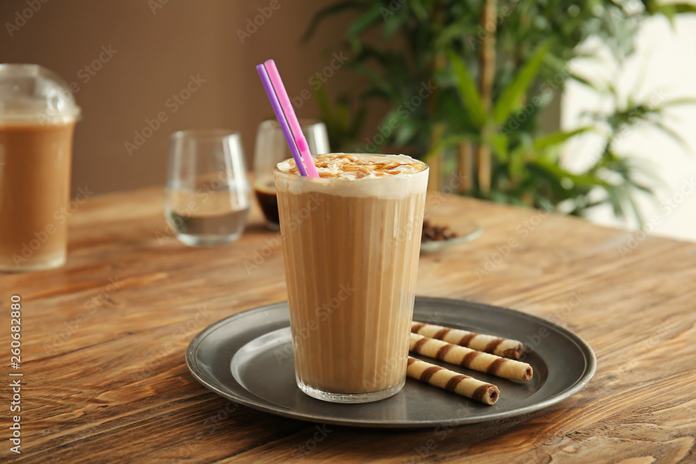 Tray with glass of tasty frappe coffee on wooden table