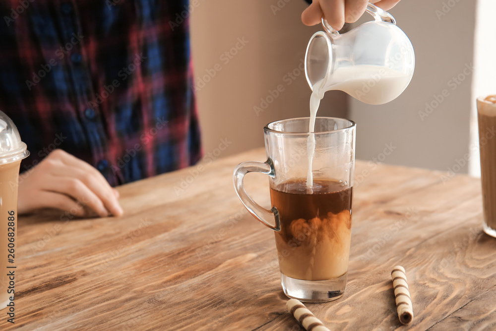 Woman preparing tasty frappe coffee on wooden table