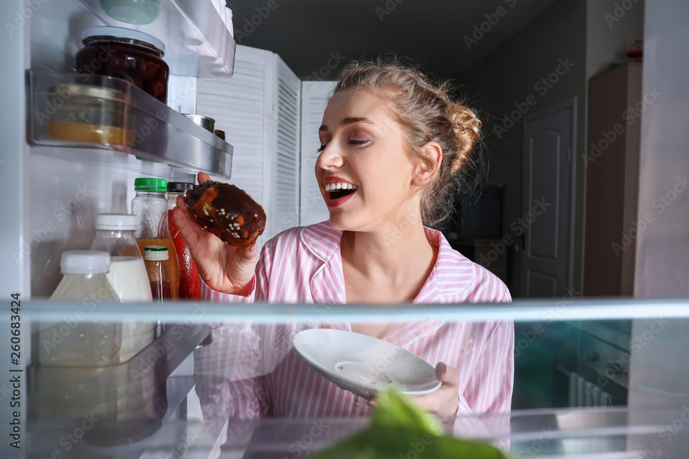 快乐的年轻女人在冰箱里挑选食物，从里面看