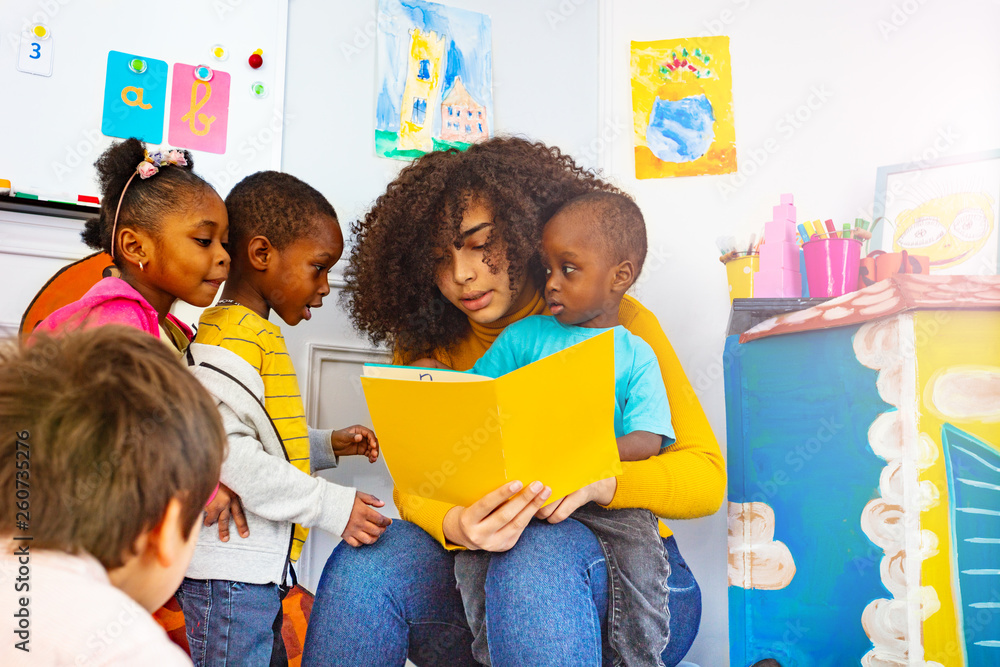 Group of little kids listen to teacher read story