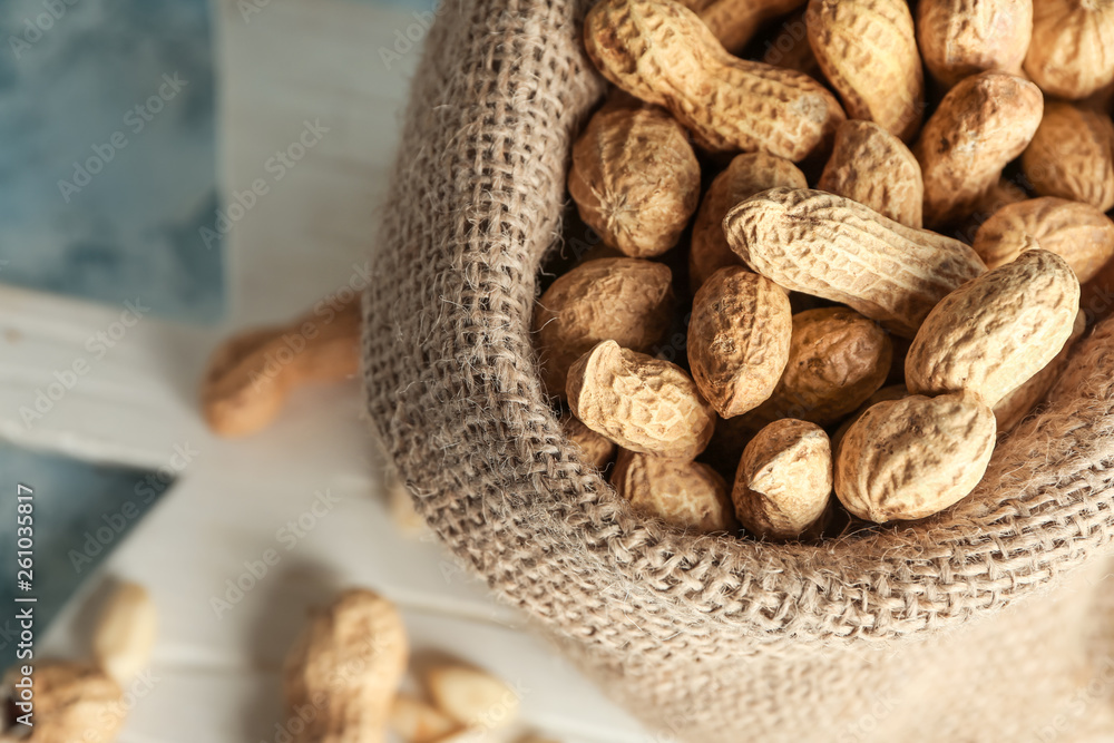 Sack with tasty peanuts on table, closeup