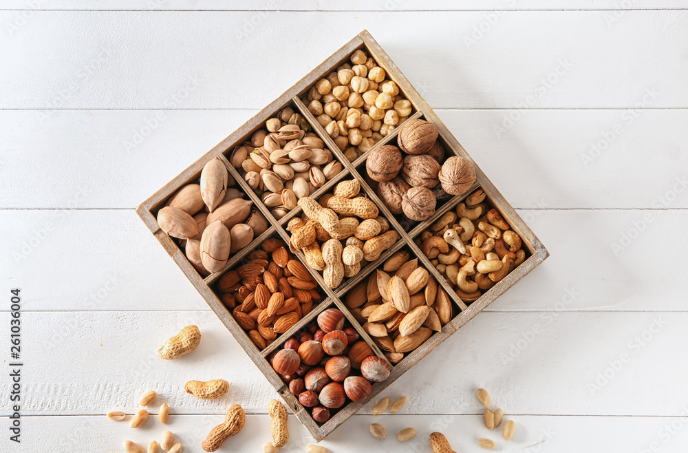 Box with different tasty nuts on white table