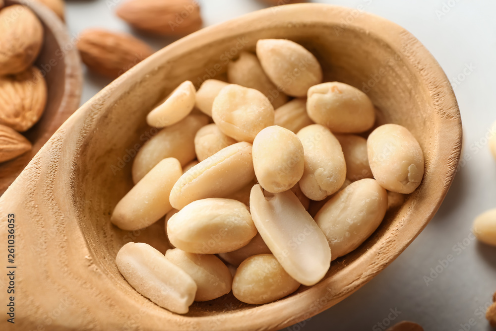 Wooden spoon with tasty peanuts on table, closeup