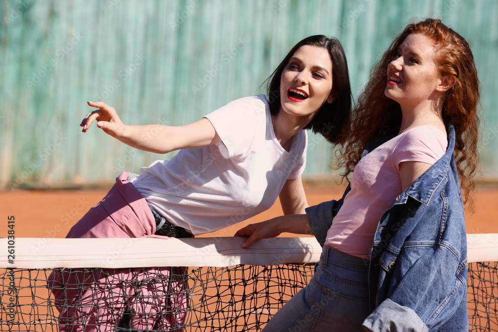 Fashionable young women on tennis court outdoors