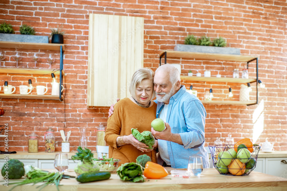 Cheerful senior couple cooking food with healthy fresh ingredients on the kitchen at home. Concept o