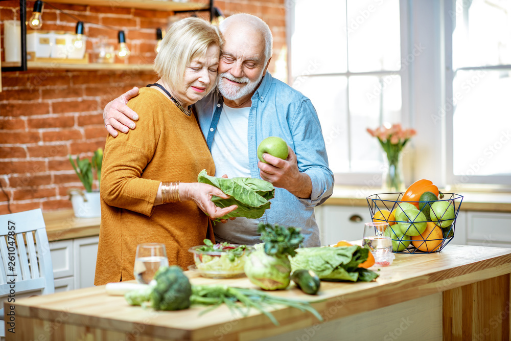 Portrait of a lovely senior couple cooking food with healthy fresh ingredients on the kitchen at hom