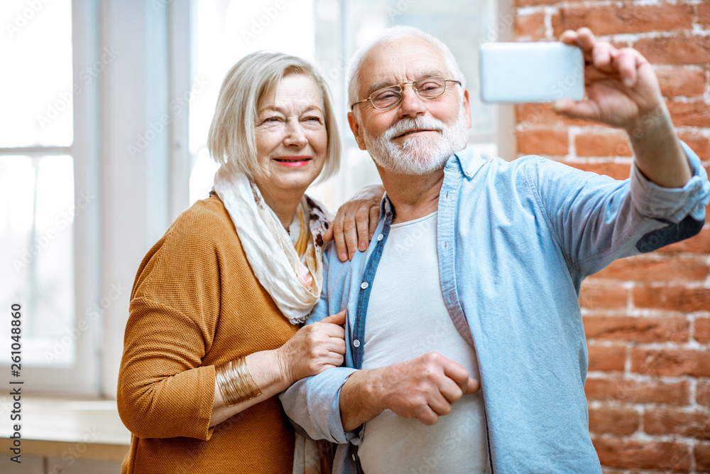 Happy senior couple making selfie photo or talking online using smart phone at home