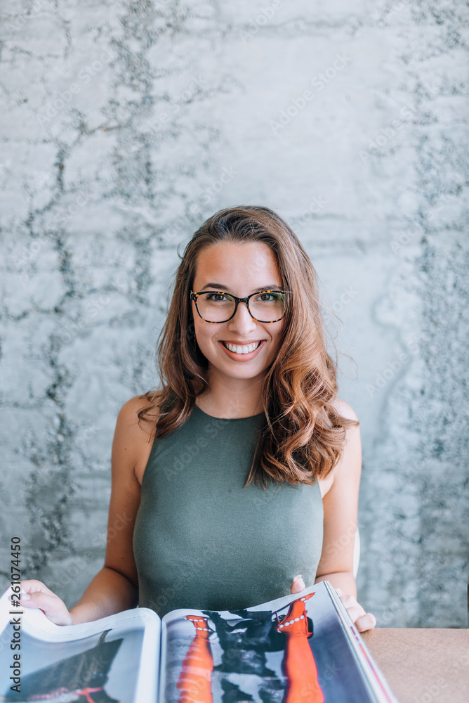 Beautiful young woman reading a magazine.