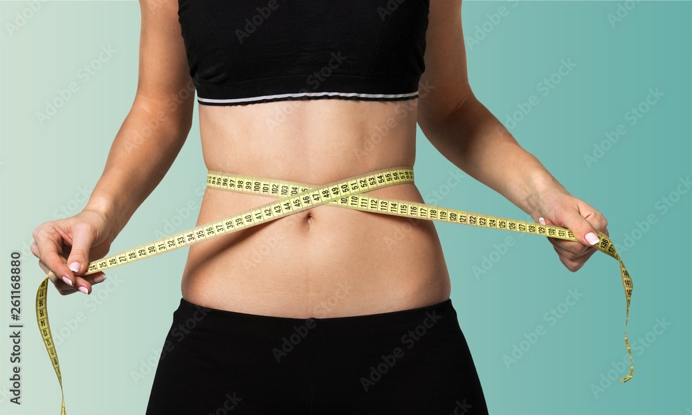 Slim young woman measuring her thin waist