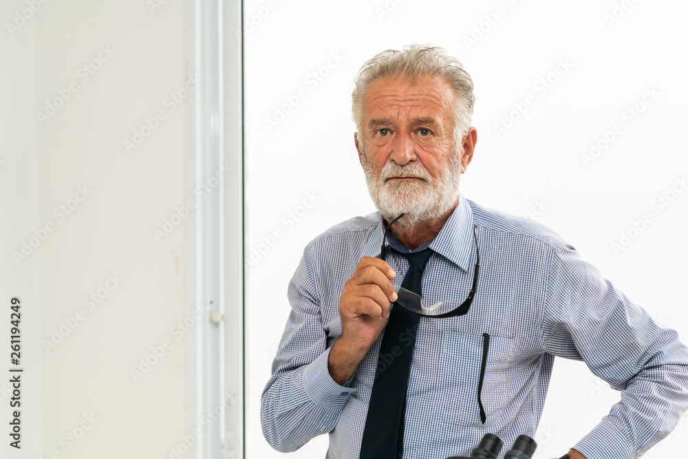 Senior adult man portrait holding eyeglasses in his hand.