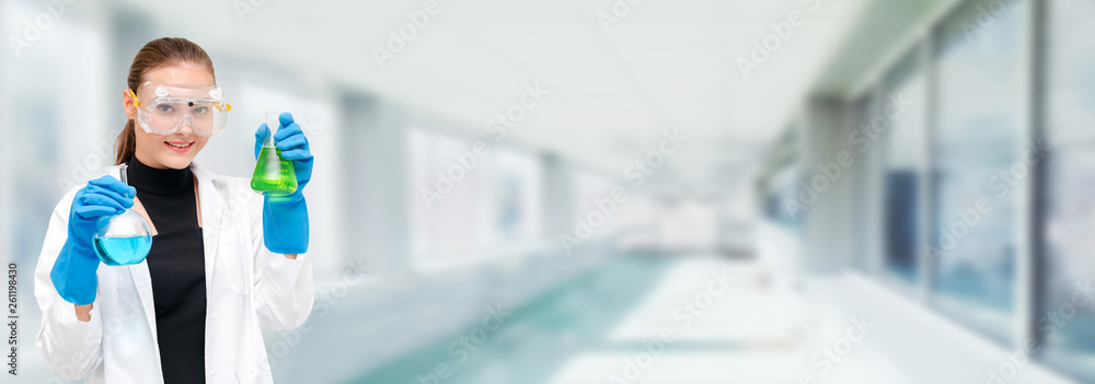 Portrait of young happy scientist or chemist holding test tube in laboratory. Chemical or medical te