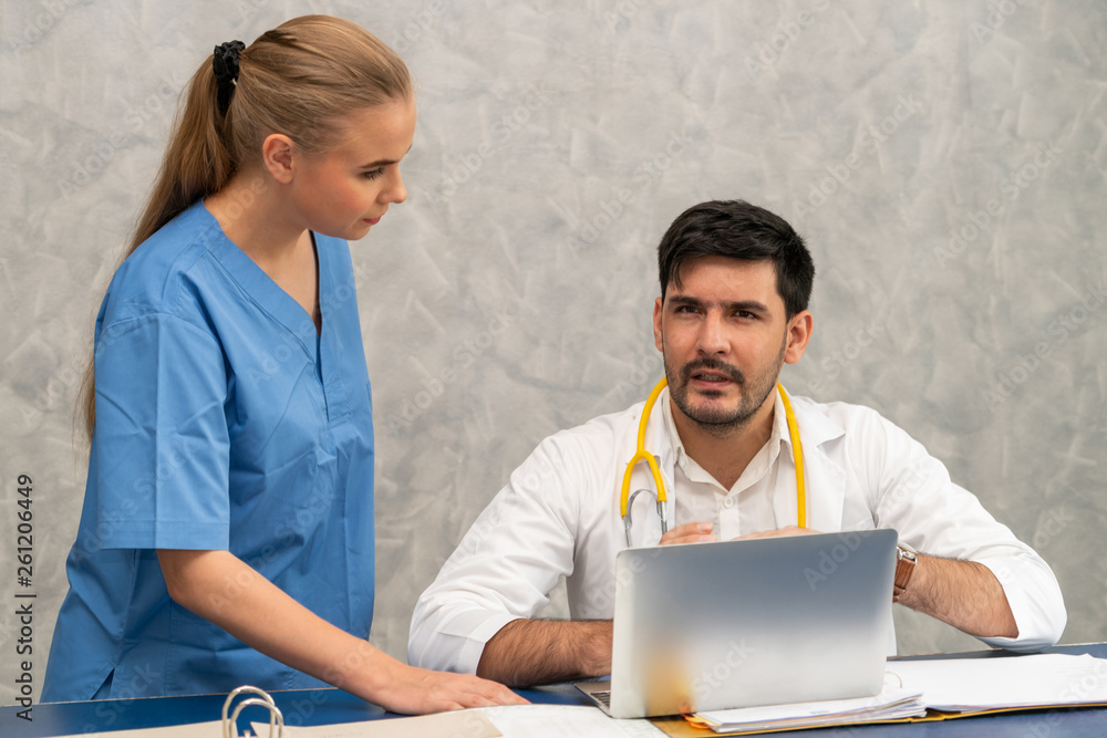 Happy doctor and nurse working with laptop computer in hospital office. Healthcare and medical conce