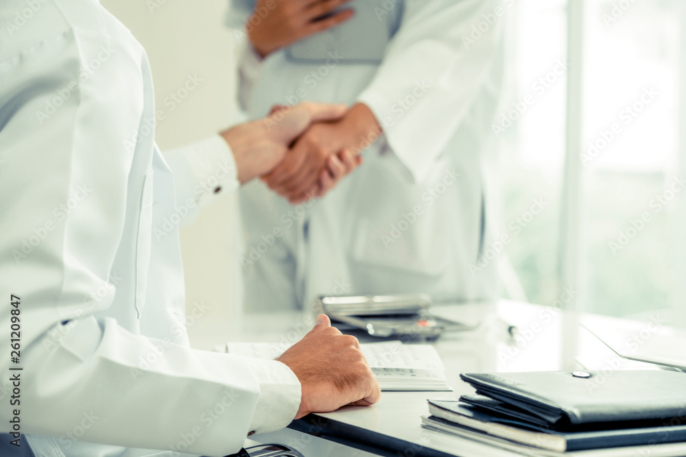 Doctor at the hospital giving handshake to another doctor showing success and teamwork of profession