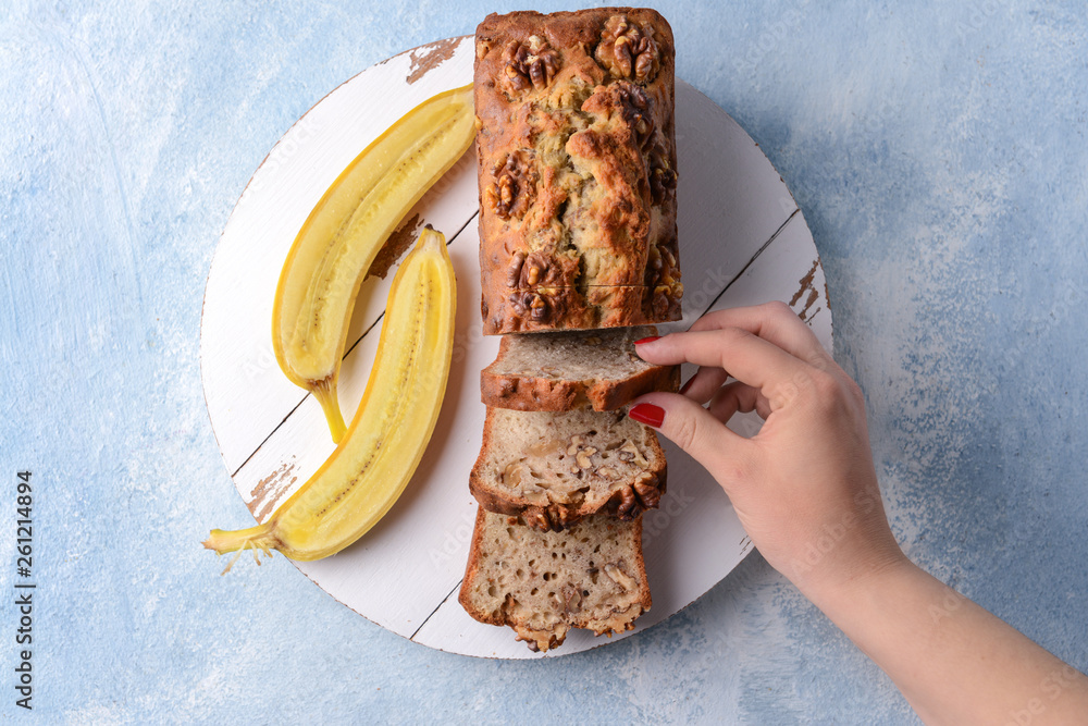 Woman taking slice of tasty banana bread from board