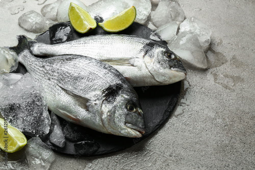 Fresh fish with ice on grey table