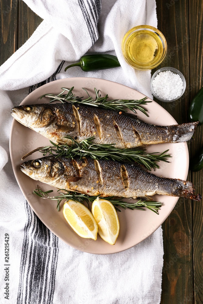 Plate with tasty cooked fish on wooden table