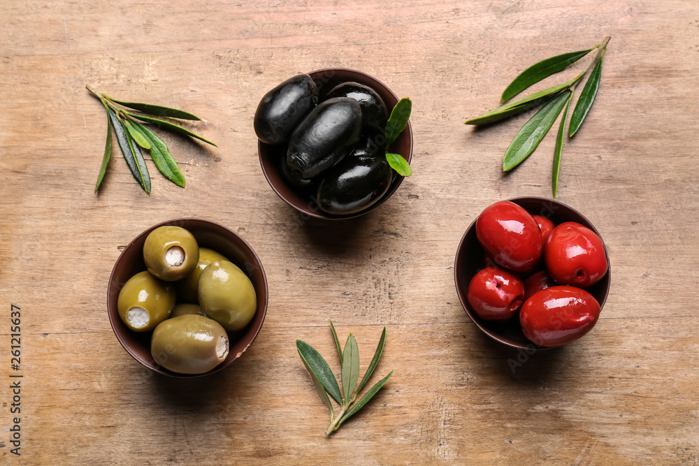 Bowls with tasty olives on wooden background