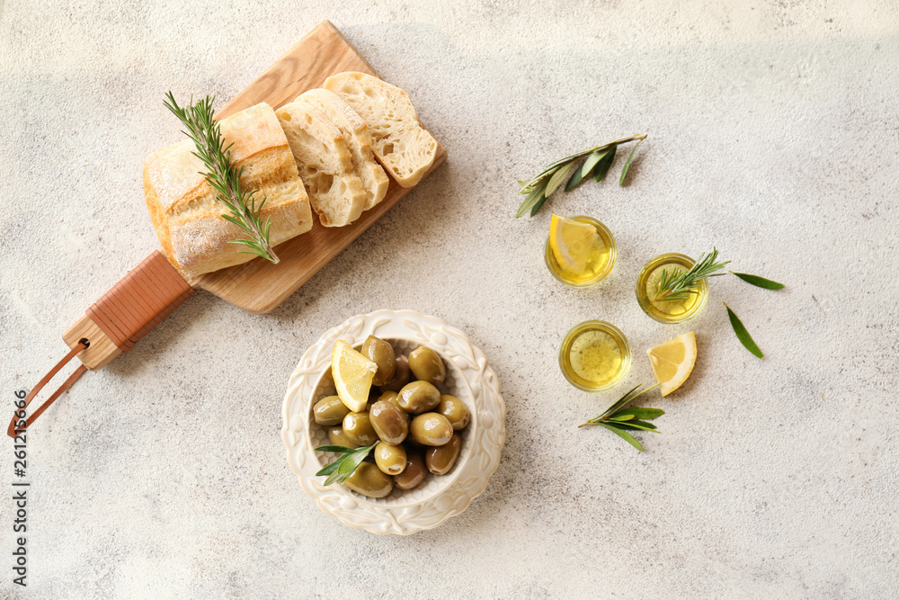 Bowl with tasty olives and fresh bread on grey background