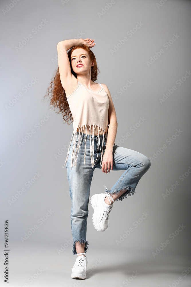 Portrait of fashionable young woman on grey background