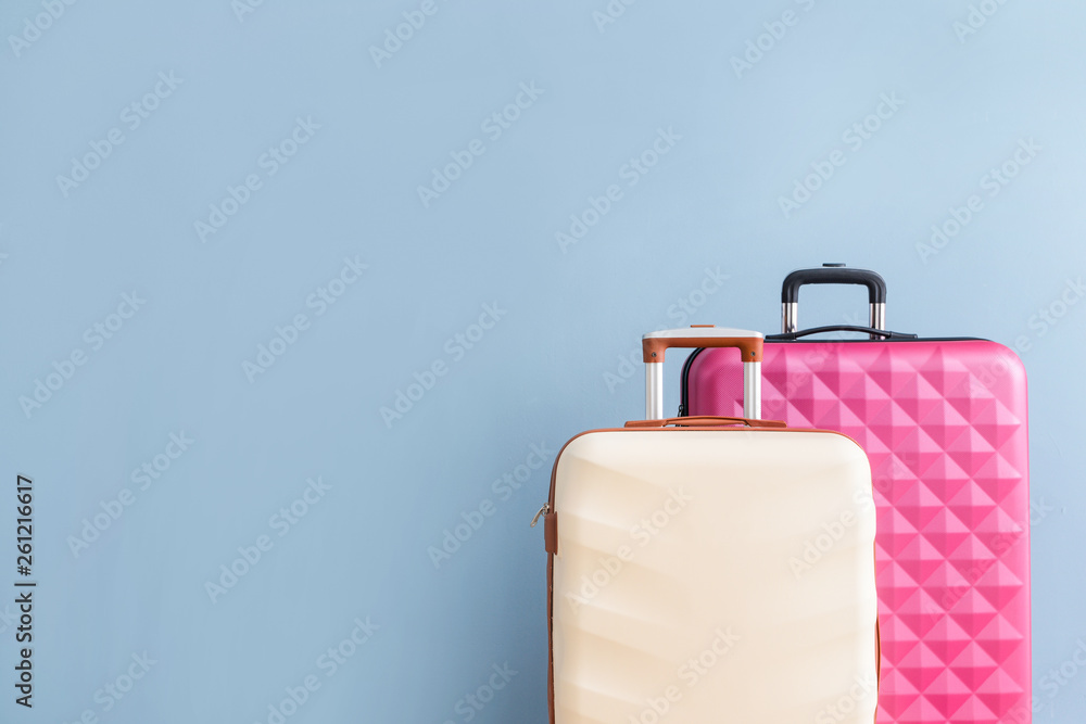 Packed suitcases on color background