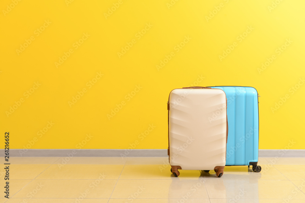 Packed suitcases near color wall