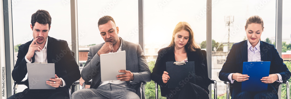 Businesswomen and businessmen holding resume CV folder while waiting on chairs in office for job int