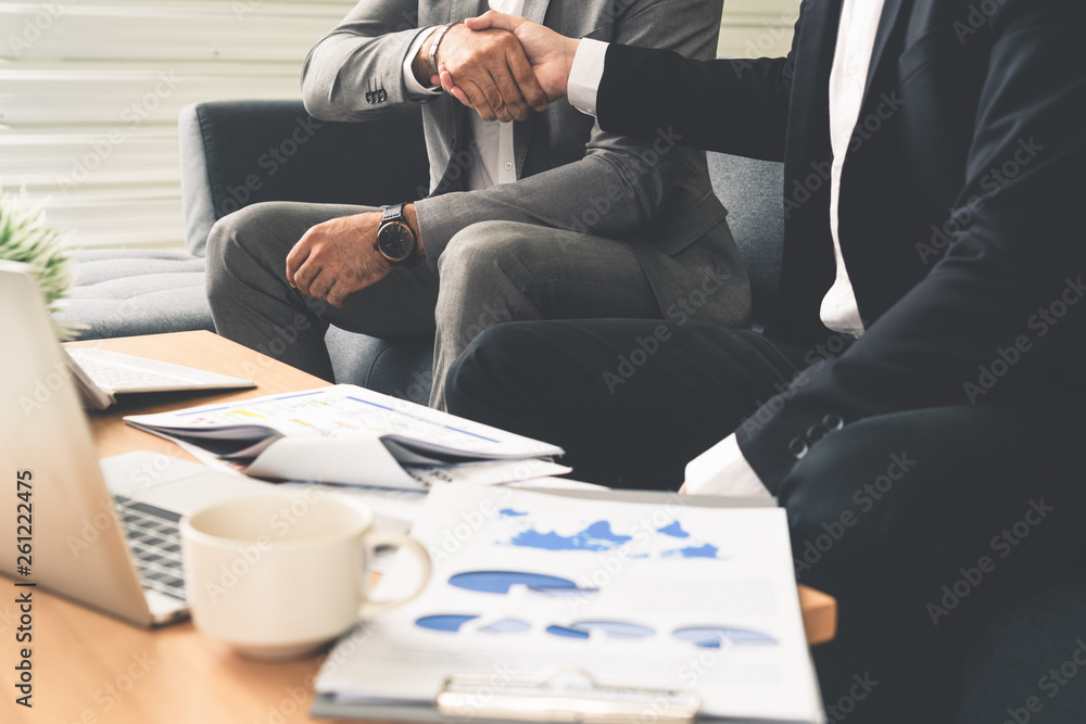 Businessman handshake with another businessman partner in modern workplace office. People corporate 