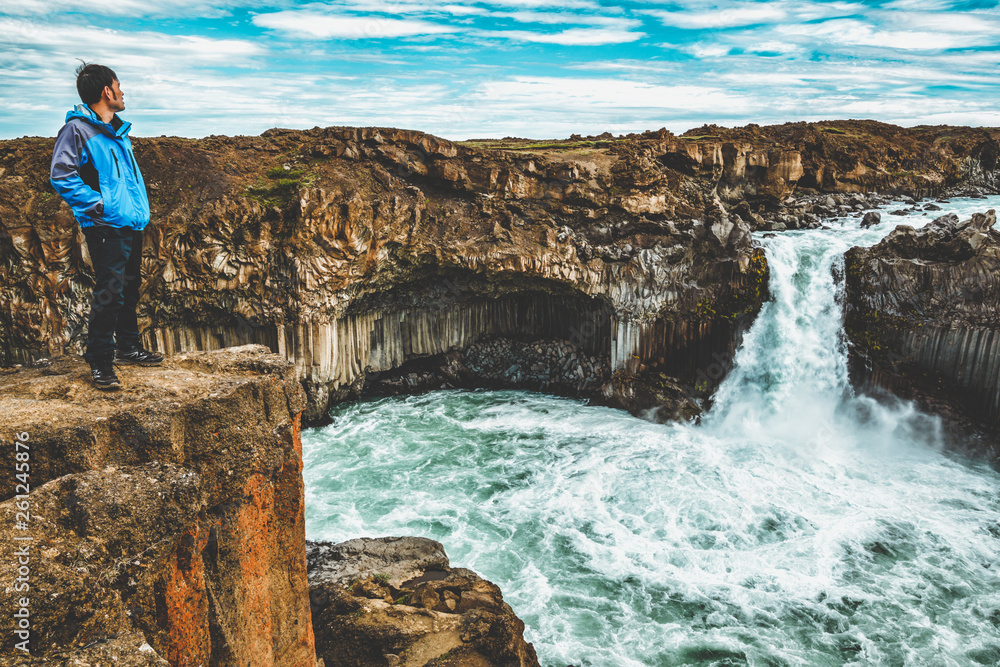 Traveler hiking in Icelandic summer landscape at the Aldeyjarfoss waterfall in north Iceland. The wa