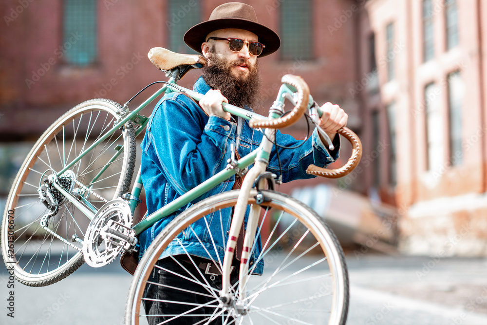 Lifestyle portrait of a bearded hipster dressed stylishly with hat and jacket carrying his retro bic