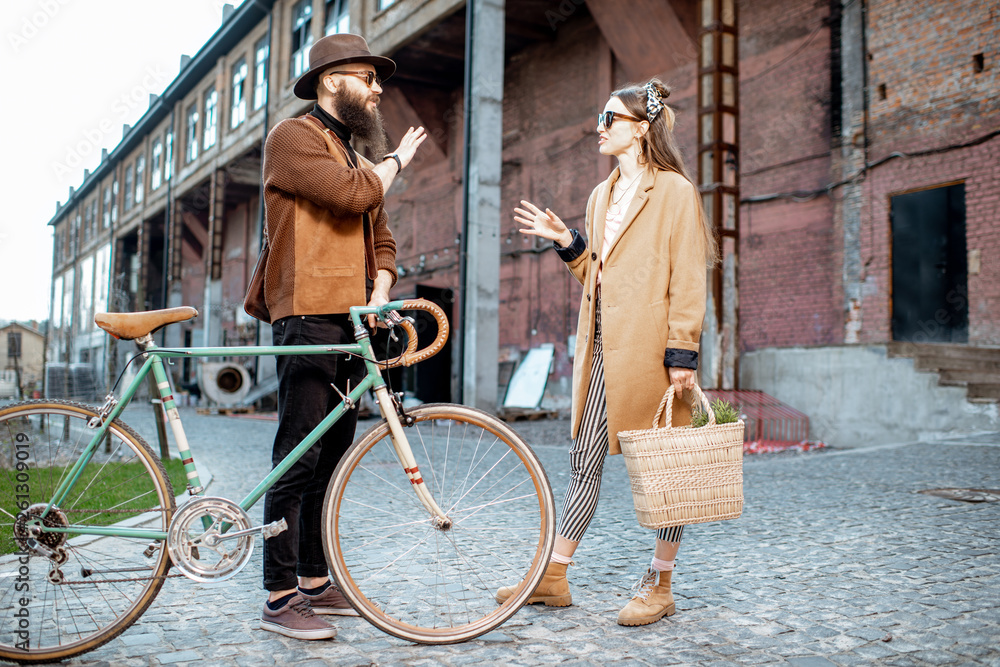 Stylish young man and woman having a conversation standing together with retro bicycle outdoors on t