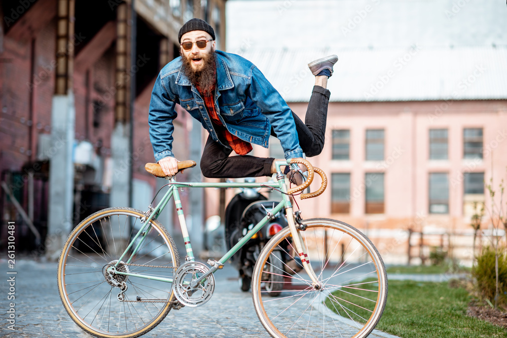 Portrait of a bearded man as a crazy hipster having fun with retro bicycle outdoors on the industria