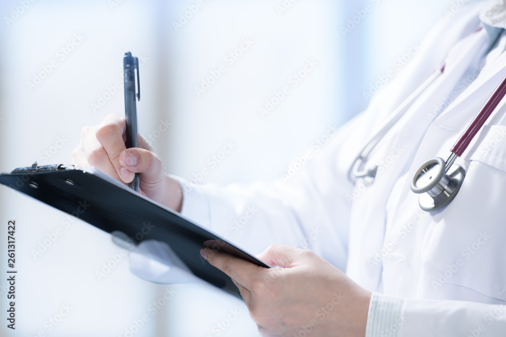 Medical doctor writing and taking notes on cliboard in hospital setting