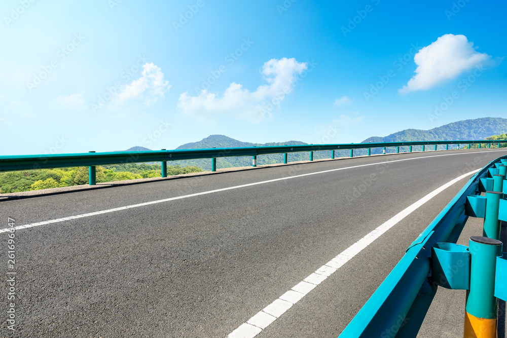 Empty asphalt road and mountains with blue sky on a sunny day