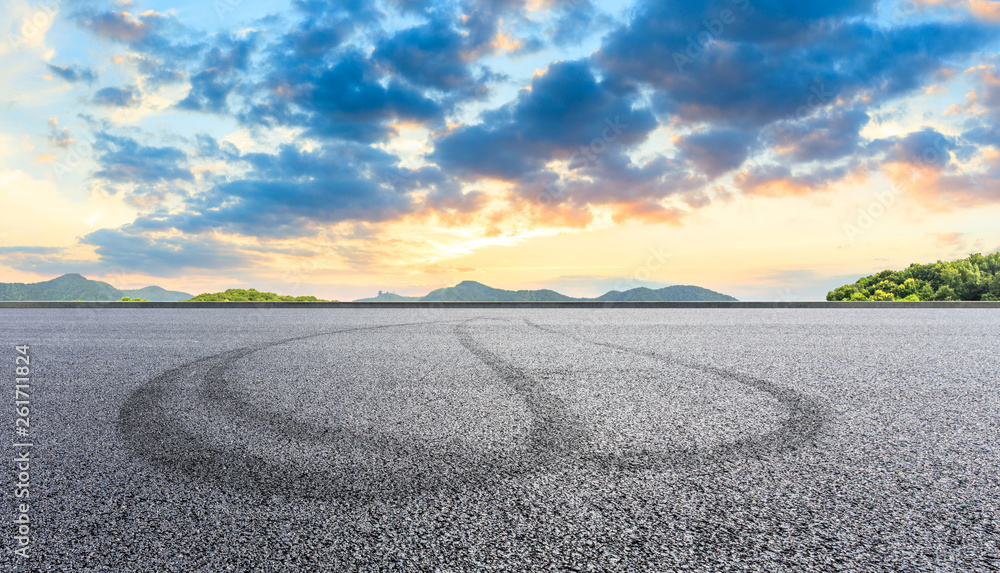 Asphalt race track ground and mountains with beautiful clouds at sunset