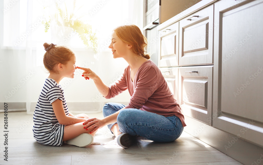 family mother and child daughter hugging in kitchen on floor