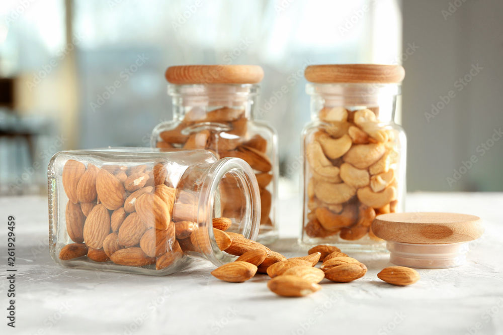 Jars with different tasty nuts on light table